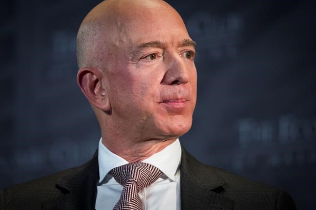 FILE- In this Sept. 13, 2018, file photo Jeff Bezos, Amazon founder and CEO, speaks at The Economic Club of Washington's Milestone Celebration in Washington. An attorney for the head of the National Enquirer’s parent company says the tabloid didn’t commit extortion or blackmail by threatening to publish Bezos’ explicit photos. Elkan Abramowitz represents American Media Inc. CEO David Pecker. He defended the tabloid’s practice as a “negotiation” in an interview Sunday, with ABC News.(AP Photo/Cliff Owen, File)