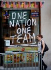 A woman walks past a sign painted on a delicatessen across the street from City Hall one day ahead of a ticker-tape parade for the U.S. Women's soccer team, four-time World Cup winners, Tuesday, July 9, 2019, in New York, NY. (AP Photo/Kathy Willens)