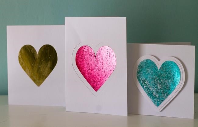This photo taken Jan. 27, 2019 shows valentine cards made in Hopkinton, N.H. Adding foil to greeting cards can turn the simplest shape into something more fancy. These cards shown here were made by applying colored foil three different ways. The gold heart was made using double-sided adhesive, the pink heart was made using a laser printer and laminating machine and the blue heart was made using a a stencil and spray adhesive. (AP Photo/Holly Ramer)