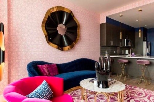 This photo provided by designer Maureen Stevens shows a room in her project in the Seaholm district of Austin, Texas. Stevens incorporated a number of chic, provocative elements, like velvet barstools on hairpin legs, a sinuous gold-legged coffee table, curvy sofa and shots of bold hues. Carefully curating dynamic accessories, textures, color and furnishings in the space keeps the look tasteful and stylish. (Lauren Logan/Maureen Stevens via AP)