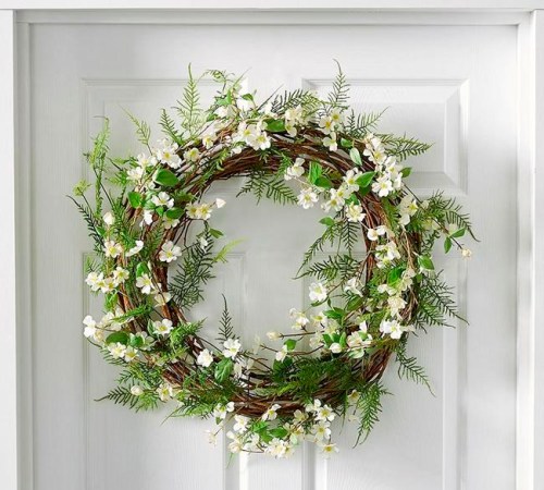 This photo provided by Pottery Barn shows pretty white flowers and faux greenery entwined to make this delicate, uplifting spring vignette in the Fern and Dogwood wreath from Pottery Barn. (Pottery Barn via AP)