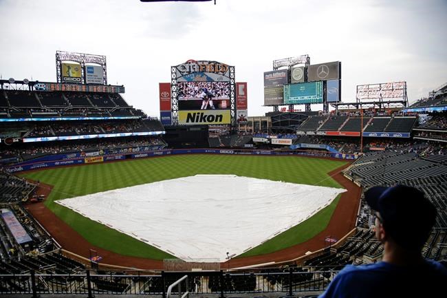 Fans wait during a rain delay in the second inning of a baseball game between the New York Mets and the Atlanta Braves, Saturday, June 29, 2019, in New York. (AP Photo/Frank Franklin II)