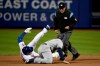 Second base umpire Phil Cuzzi, top, looks on as New York Mets' Travis d'Arnaud, left, is tagged out by Milwaukee Brewers second baseman Mike Moustakas, center, while trying to stretch a single off relief pitcher Alex Wilson during the seventh inning of a baseball game, Saturday, April 27, 2019, in New York. (AP Photo/Julio Cortez)