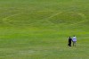 Carol Laura, left, and George Acquaire walk barefoot to a peace sign mowed in the grass at the site of the 1969 Woodstock Music and Arts Fair, Wednesday, July 24, 2019 in Bethel, N.Y. Woodstock will be celebrated on its 50th anniversary, but it won't be your hippie uncle's trample-the-fences concert. While plans for a big Woodstock 50 festival collapsed after a run of calamities, the bucolic upstate New York site of the 1969 show is hosting a long weekend of events featuring separate shows by festival veterans like Carlos Santana and John Fogerty. (AP Photo/Seth Wenig)