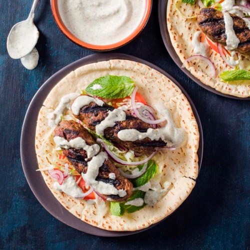 This undated photo provided by America's Test Kitchen in May 2019 shows Grilled Lamb Kofte with Yogurt Sauce in Brookline, Mass. This recipe appears in the cookbook “Spiced.” (Carl Tremblay/America's Test Kitchen via AP)