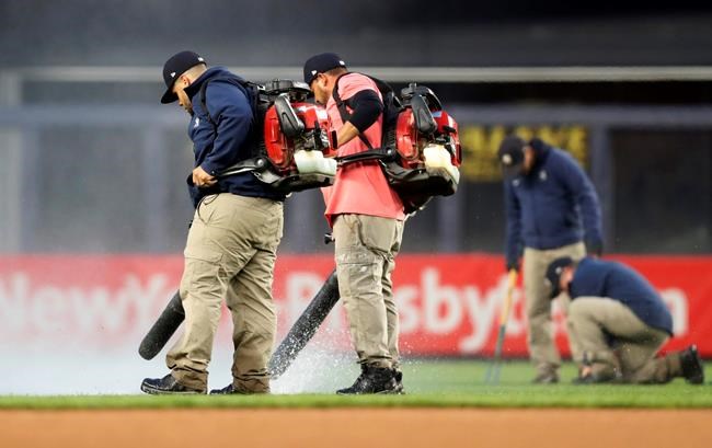 Groundskeepers use leaf blowers to remove rainwater from the field at Yankee Stadium before a baseball game between the New York Yankees and the Baltimore Orioles, Monday, May 13, 2019, in New York. The game was postponed until Wednesday afternoon due to unplayable field conditions. (AP Photo/Kathy Willens)