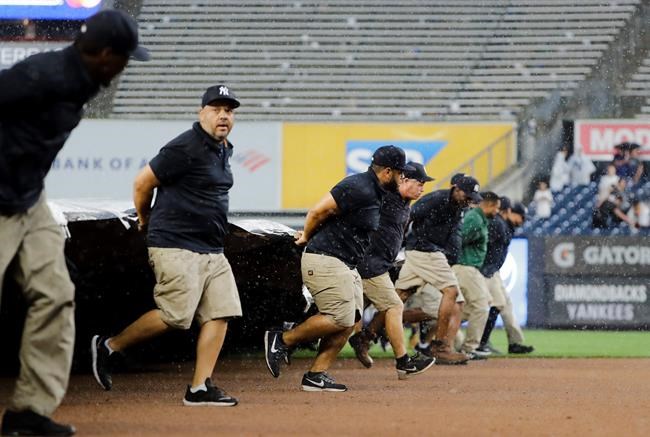 Grounds crew at Yankee Stadium cover the field during a rain delay during the sixth inning of a baseball game between the New York Yankees and the Arizona Diamondbacks Wednesday, July 31, 2019, in New York. (AP Photo/Frank Franklin II)
