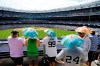 Fans use umbrella hats to protect themselves from the sun during the sixth inning of a baseball game between the New York Yankees and the Colorado Rockies Saturday, July 20, 2019, in New York. (AP Photo/Frank Franklin II)