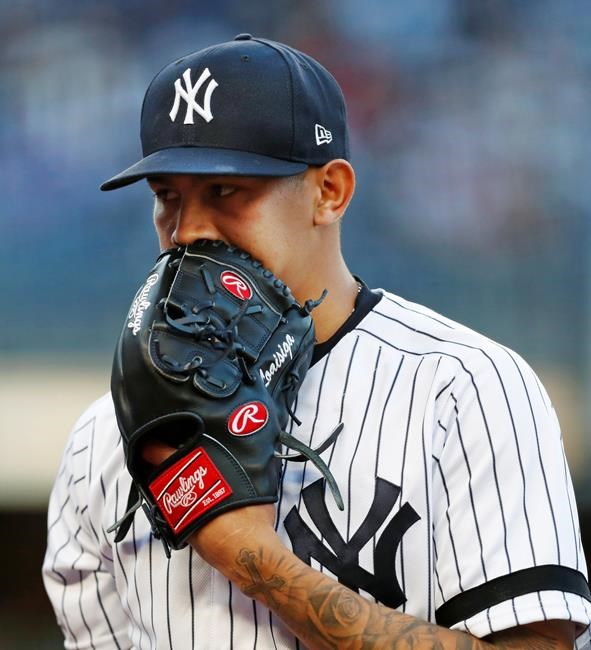 New York Yankees starting pitcher Jonathan Loaisiga (43) talks into his glove coming off the mound after allowing a run during the first inning of a baseball game against the Seattle Mariners, Wednesday, May 8, 2019, in New York. (AP Photo/Kathy Willens)