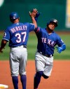 Texas Rangers' Willie Calhoun, right, gets a high-five from third base coach Tony Beasley (37) after hitting a solo home run off Oakland Athletics starting pitcher Tanner Roark during the first inning of a baseball game Sunday, Sept. 22, 2019, in Oakland, Calif. (AP Photo/D. Ross Cameron)