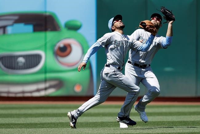 Seattle Mariners' J.P. Crawford, left, and Mac Williamson chase a fly ball hit by Oakland Athletics' Khris Davis in the sixth inning of a baseball game Sunday, June 16, 2019, in Oakland, Calif. Crawford made the catch. (AP Photo/Ben Margot)