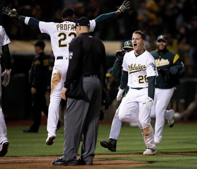 Oakland Athletics' Matt Chapman (26) celebrates with Jurickson Profar (23) after hitting a three-run, game-winning home run off Tampa Bay Rays' Diego Castillo in a baseball game Thursday, June 20, 2019, in Oakland, Calif. (AP Photo/Ben Margot)