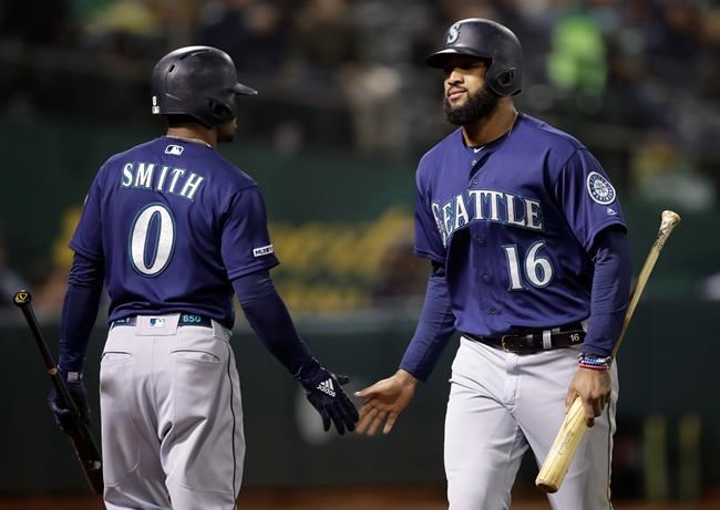Seattle Mariners' Domingo Santana, right, is congratulated by Mallex Smith (0) after scoring against the Oakland Athletics during the seventh inning of a baseball game Friday, May 24, 2019, in Oakland, Calif. (AP Photo/Ben Margot)