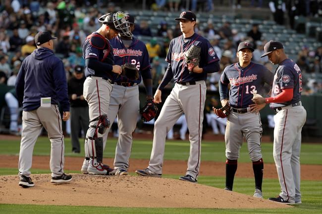 Minnesota Twins pitcher Kyle Gibson, center, waits to speak to pitching coach Wes Johnson, left, in the second inning of a baseball game against the Oakland Athletics Wednesday, July 3, 2019, in Oakland, Calif. (AP Photo/Ben Margot)