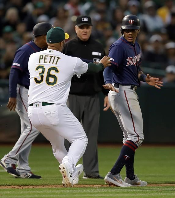 Minnesota Twins' Ehire Adrianza, right, is tagged out stealing home by Oakland Athletics pitcher Yusmeiro Petit in the seventh inning of a baseball game Wednesday, July 3, 2019, in Oakland, Calif. (AP Photo/Ben Margot)