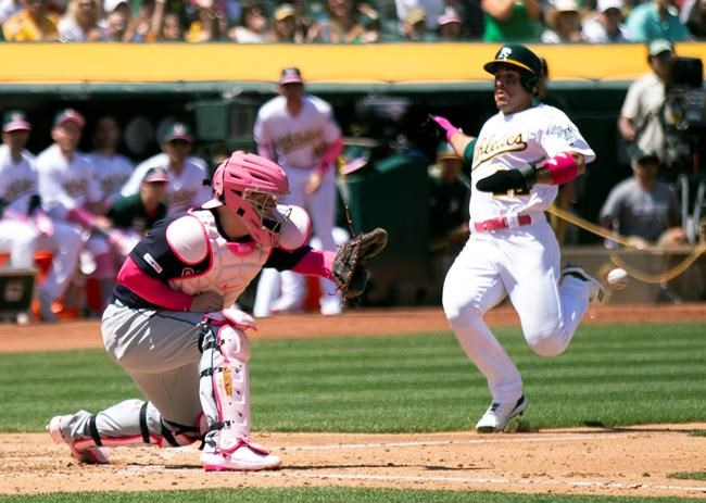 Oakland Athletics' Ramon Laureano (22) scores from second base on Stephen Piscotty's RBI single as Cleveland Indians catcher Roberto Perez (55) awaits the tardy relay during the third inning of a baseball game, Sunday, May 12, 2019, in Oakland, Calif. (AP Photo/D. Ross Cameron)