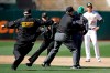 Second base umpire Jeff Nelson (45) grabs a fan that ran onto the field as security guards assist and Oakland Athletics' Stephen Piscotty, right, watches in the ninth inning of a baseball game against the Toronto Blue Jays, Saturday, April 20, 2019, in Oakland, Calif. (AP Photo/Ben Margot)
