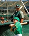 Eight-year-old August Wold swings in front of Oakland Athletics' Marcus Semien during batting practice prior to a baseball game against the Texas Rangers, Saturday, July 27, 2019, in Oakland, Calif. All this 8-year-old Little Leaguer wants is to play for the A's. They gave Wold the closest next thing with a mock contract and signing, complete with a news release announcing the deal, in collaboration with the Make-A-Wish Foundation. (AP Photo/Ben Margot)