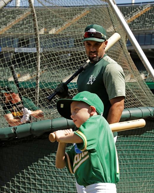 Eight-year-old August Wold swings in front of Oakland Athletics' Marcus Semien during batting practice prior to a baseball game against the Texas Rangers, Saturday, July 27, 2019, in Oakland, Calif. All this 8-year-old Little Leaguer wants is to play for the A's. They gave Wold the closest next thing with a mock contract and signing, complete with a news release announcing the deal, in collaboration with the Make-A-Wish Foundation. (AP Photo/Ben Margot)