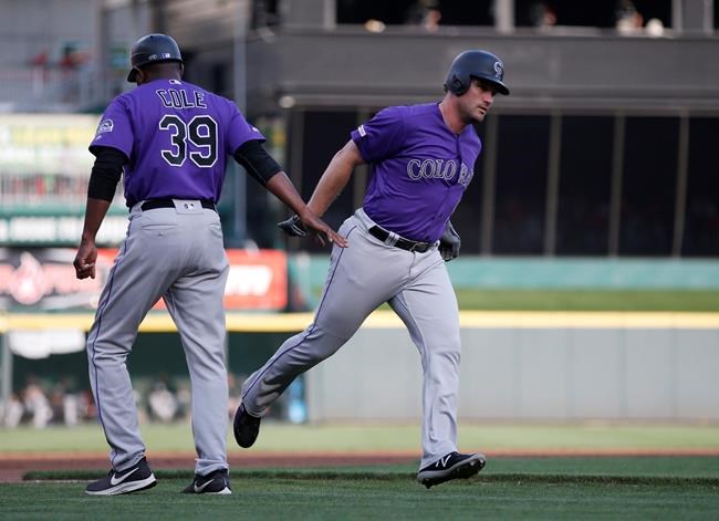 Colorado Rockies' Daniel Murphy, right, is congratulated on a three-run home run off Cincinnati Reds starting pitcher Luis Castillo by third base coach Stu Cole (39) during the first inning of a baseball game, Friday, July 26, 2019, in Cincinnati. (AP Photo/Gary Landers)
