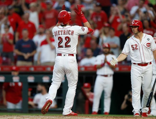 Cincinnati Reds' Derek Dietrich (22) raises his arms as he crosses home plate with a two-run home run off Pittsburgh Pirates relief pitcher Geoff Hartlieb during the seventh inning of a baseball game, Tuesday, May 28, 2019, in Cincinnati. At right is Reds catcher Kyle Farmer (52). (AP Photo/Gary Landers)