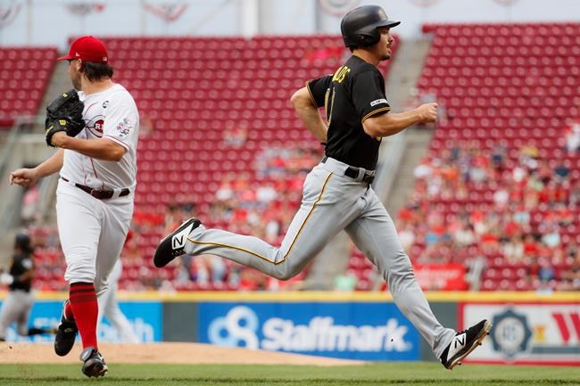 Pittsburgh Pirates' Bryan Reynolds, right, runs home to score on a two-run double hit by Josh Bell off Cincinnati Reds starting pitcher Tanner Roark, left, in the first inning of a baseball game, Tuesday, July 30, 2019, in Cincinnati. (AP Photo/John Minchillo)