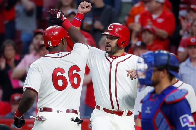 Cincinnati Reds' Yasiel Puig (66) celebrates with Eugenio Suarez, center, after hitting a two-run home run off Texas Rangers starting pitcher Mike Minor during the fourth inning of a baseball game Saturday, June 15, 2019, in Cincinnati. (AP Photo/John Minchillo)