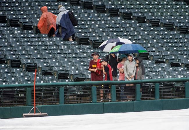Die-hard Cleveland Indians fans hang out at Progressive Field after a baseball game against the Texas Rangers was called due to rain in Cleveland, Tuesday, Aug. 6, 2019. (AP Photo/Phil Long)