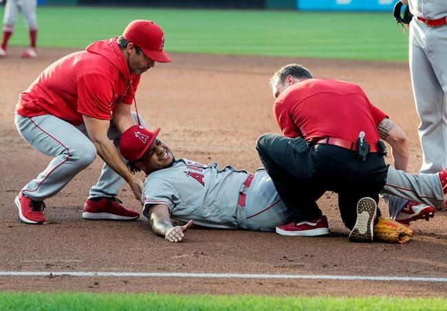 Los Angeles Angels starting pitcher Felix Pena, center, is tended to by trainers after an injury while covering first base during the second inning of a baseball game against the Cleveland Indians in Cleveland, Saturday, Aug. 3, 2019. (AP Photo/Phil Long)