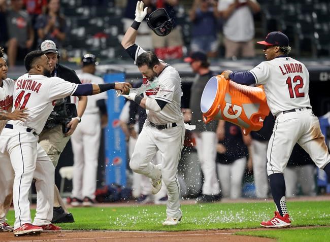 Cleveland Indians' Jason Kipnis, center, is doused with water from Cleveland Indians' Carlos Santana, left, and Francisco Lindor, right, after hitting a solo home run in the 10th inning in a baseball game against the Kansas City Royals, Tuesday, June 25, 2019, in Cleveland. The Indians won 3-2 in 10 innings. (AP Photo/Tony Dejak)