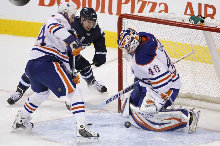John Woods / Winnipeg Free Press
Winnipeg Jets' Kyle Wellwood (13) and Edmonton Oilers' Ryan Smyth (94) fight for position as Oilers' goaltender Devan Dubnyk (40) covers the rebound during first-period NHL action in Winnipeg on Monday.