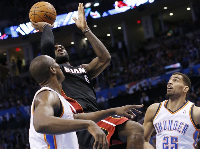 Miami Heat forward LeBron James (6) shoots between Oklahoma City Thunder forward Serge Ibaka (9) and guard Thabo Sefolosha (25) during the second quarter of an NBA basketball game in Oklahoma City, Thursday, Feb. 20, 2014. (AP Photo/Sue Ogrocki)