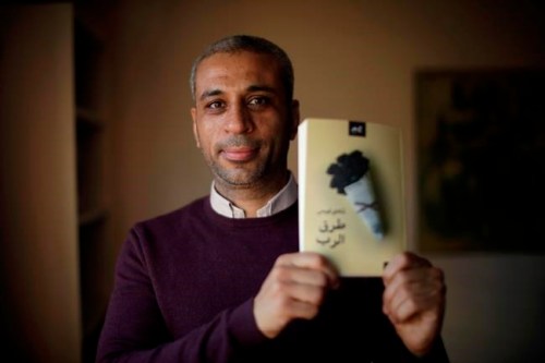 In this Tuesday, Dec. 4, 2018 photo, journalist and author Shady Lewis Botros poses with a copy of his book, 