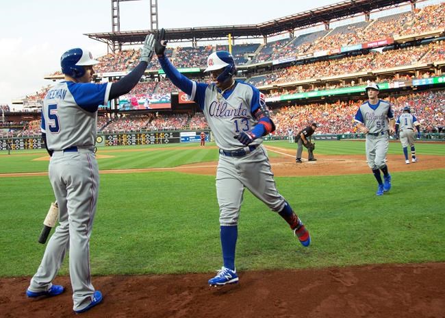 Atlanta Braves' Ronald Acuna Jr., center, gets a high five from Freddie Freeman, left, after hitting a two-run home run, which scored Max Fried, right, during the second inning of a baseball game against the Philadelphia Phillies, Saturday, July 27, 2019, in Philadelphia. (AP Photo/Chris Szagola)
