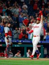 Philadelphia Phillies' Bryce Harper, right, gestures as he scores on his three-run home run, next to Washington Nationals catcher Yan Gomes during the third inning of a baseball game Tuesday, April 9, 2019, in Philadelphia. (AP Photo/Chris Szagola)