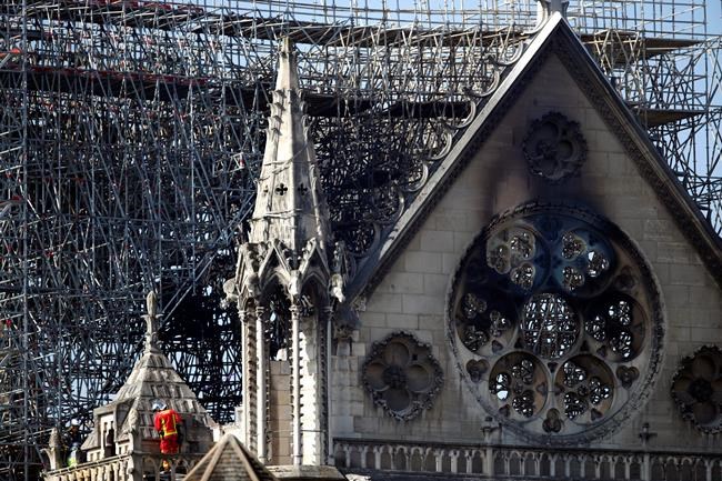 A fire fighter makes his way on a balcony of Notre Dame cathedral Wednesday, April 17, 2019 in Paris. French President Emmanuel Macron ratcheted up the pressure by setting a five-year deadline to restore the 12th-century landmark. (AP Photo/Francois Mori)