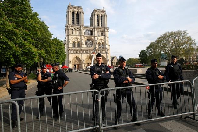 Police officer stand behind the security barriers in front of Notre Dame cathedral Thursday, April 18, 2019 in Paris. France paid a daylong tribute Thursday to the Paris firefighters who saved Notre Dame Cathedral from collapse, while construction workers rushed to secure an area above one of the church's famed rose-shaped windows and other vulnerable sections of the fire-damaged landmark. (AP Photo/Michel Euler, Pool)