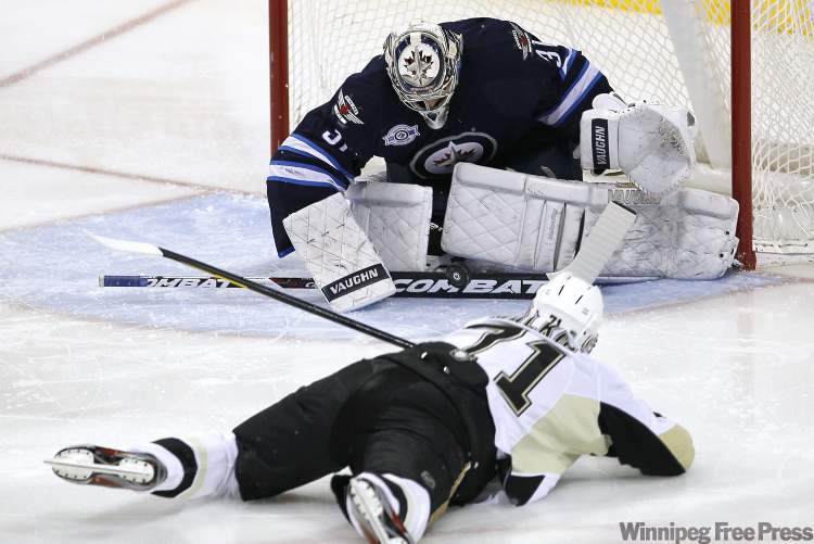 John Woods / The Canadian Press
Penguins forward Evgeni Malkin gets a shot off while on his belly, but Jets goalie Ondrej Pavelec is equal to the task.