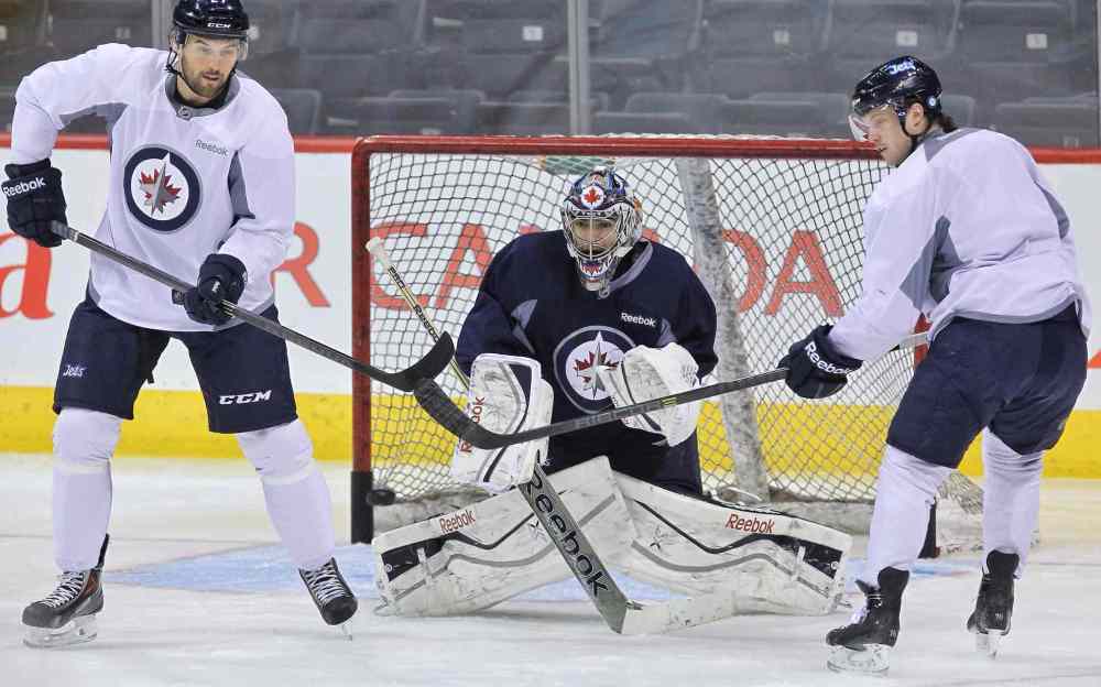 Mike Deal / Winnipeg Free Press
Winnipeg Jets' Eric Tangradi (27) and John Albert (70) try to deflect an incoming puck in front of goaltender Al Montoya (35) during a very short practice Sunday morning at MTS Centre.