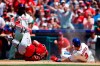 Cincinnati Reds catcher Curt Casali, left, tumbles after a collision at home plate with Philadelphia Phillies' Bryce Harper on a two-run single by Rhys Hoskins during the third inning of a baseball game, Sunday, June 9, 2019, in Philadelphia. Harper was safe on the play. (AP Photo/Matt Slocum)