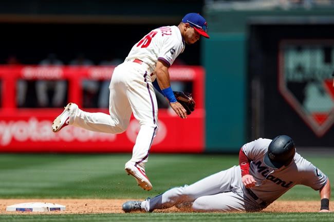 Philadelphia Phillies second baseman Cesar Hernandez, left, leaps to avoid Miami Marlins' Garrett Cooper after forcing him out at second on a run-scoring double play hit by Brian Anderson during the third inning of a baseball game, Sunday, June 23, 2019, in Philadelphia. Anderson was out at first on the play. (AP Photo/Matt Slocum)