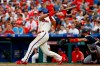 Philadelphia Phillies' J.T. Realmuto, left, follows through after hitting a two-run home run off Atlanta Braves relief pitcher Wes Parsons during the fifth inning of a baseball game, Saturday, March 30, 2019, in Philadelphia. Braves catcher Tyler Flowers, right, looks on. (AP Photo/Matt Slocum)