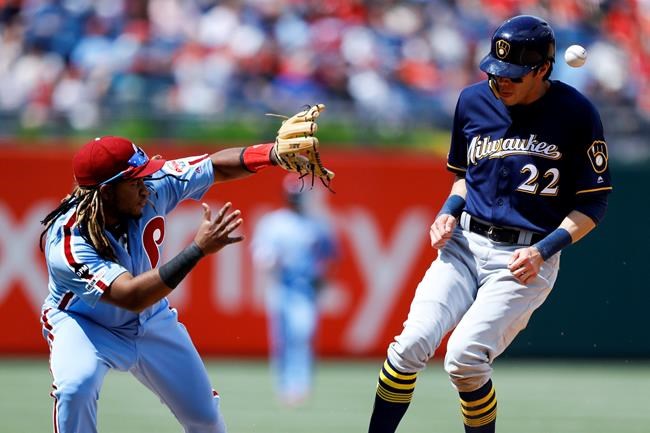 Milwaukee Brewers' Christian Yelich, right, is hit by a throw near Philadelphia Phillies third baseman Maikel Franco after Yelich advanced to third on an overthrow after stealing second during the sixth inning of a baseball game, Thursday, May 16, 2019, in Philadelphia. (AP Photo/Matt Slocum)