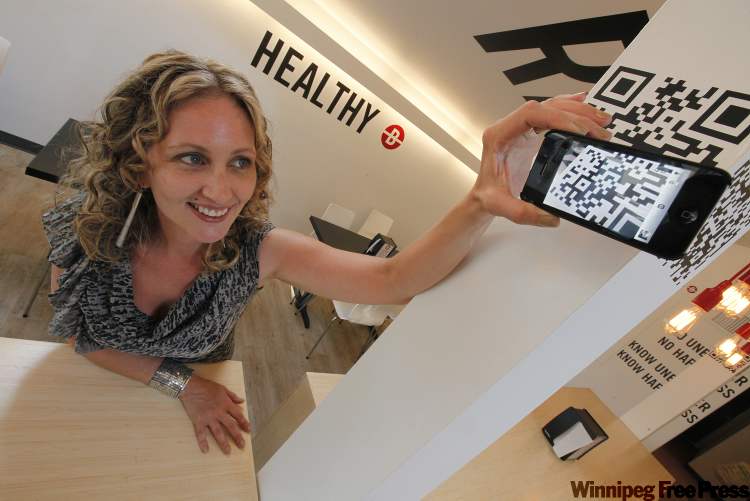 John Woods / Winnipeg Free Press
Erica Glasier, marketer and blogger at Tactica Interactive, scans a QR code at Unburger in Osborne Village in Winnipeg, Saturday.