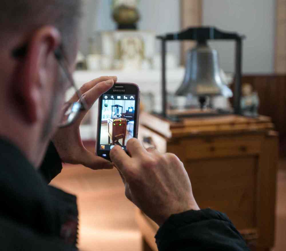 A visitor to the St. Boniface Museum on Louis Riel Day snaps a photo of the Bell of Batoche on display inside the museum. (Melissa Tait / Winnipeg Free Press files)