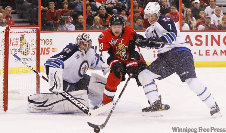 Jean Levac / Postmedia Ottawa Citizen
Jesse Winchester (M) of the Ottawa Senators is pushed by Derek Meech (R) as Ondrej Pavelec (L) of the Winnipeg Jets looks on during first period NHL action in Ottawa Thursday.