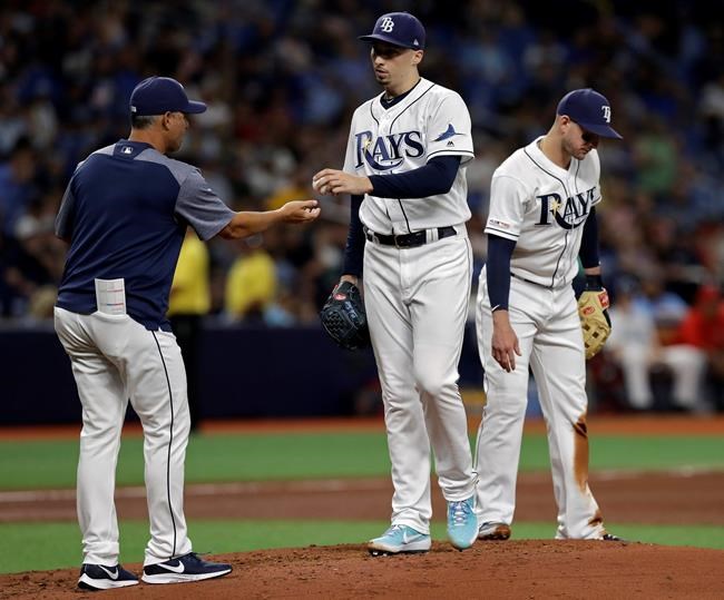 Tampa Bay Rays starting pitcher Blake Snell, center, hands the ball to manager Kevin Cash, left, as he is taken out of the baseball game against the Los Angeles Angels during the fourth inning Friday, June 14, 2019, in St. Petersburg, Fla. Looking away is third baseman Daniel Robertson. (AP Photo/Chris O'Meara)