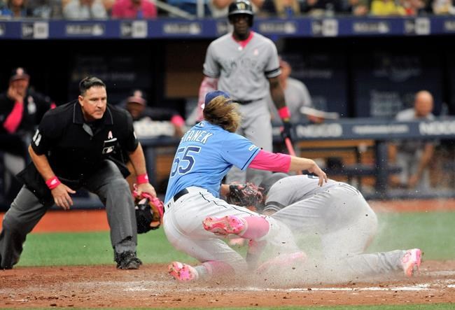 Home plate umpire Tony Randazzo, left, watches as Tampa Bay Rays pitcher Ryne Stanek, center, tries to tag out New York Yankees' Luke Voit, right, at the plate during the eighth inning of a baseball game Sunday, May 12, 2019, in St. Petersburg, Fla. Voit scored on a wild pitch thrown by Stanek. (AP Photo/Steve Nesius)