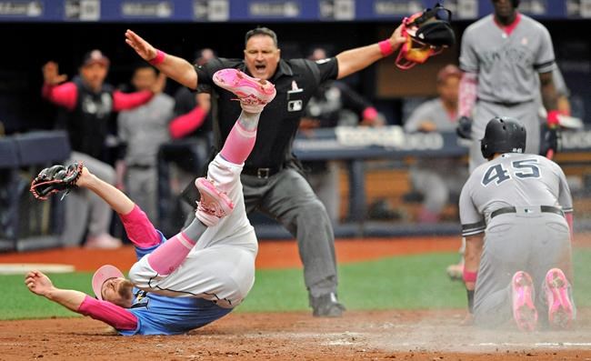 Home plate umpire Tony Randazzo, center, makes the call as Tampa Bay Rays pitcher Ryne Stanek, center, tumbles after trying to tag out New York Yankees' Luke Voit (45) in a collision at the plate during the eighth inning of a baseball game Sunday, May 12, 2019, in St. Petersburg, Fla. Voit scored on a wild pitch thrown by Stanek. (AP Photo/Steve Nesius)