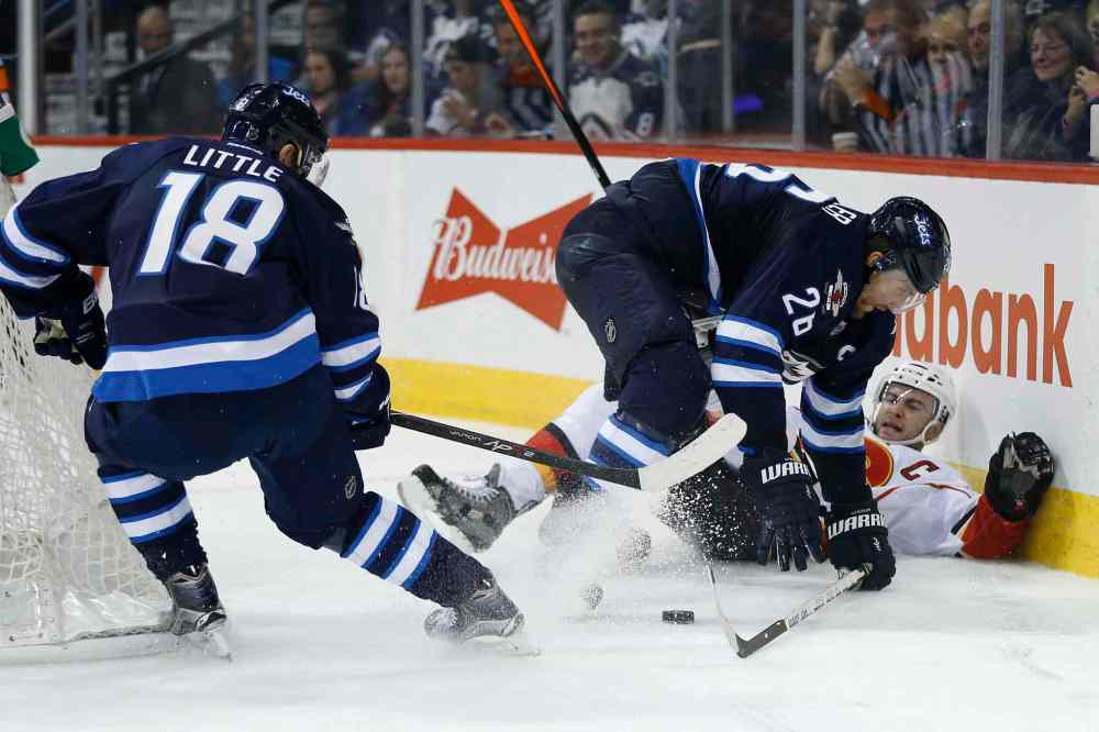John Woods / The Canadian Press
Winnipeg Jets' Blake Wheeler, second right, checks Calgary Flames' Mark Giordano, right, as Jets' Bryan Little (18) picks up the loose puck during second period NHL action in Winnipeg on Friday.